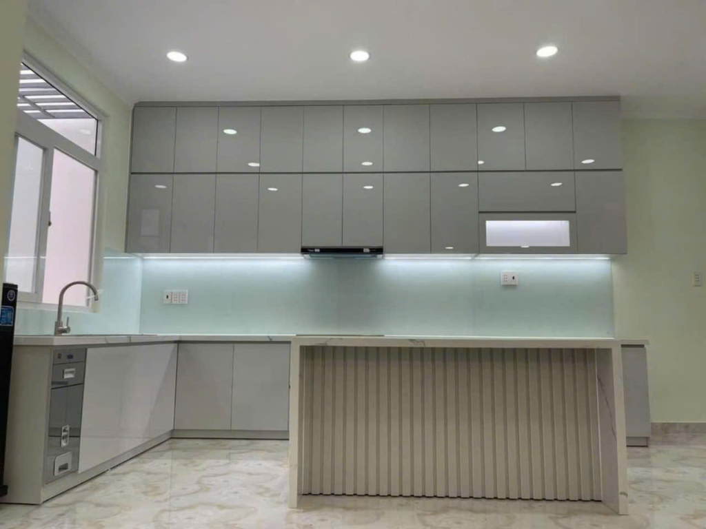 Mẫu tủ bếp 21 | Nội Thất SHC Tủ bếp trắng bề mặt bóng với đảo ốp nan và đèn chiếu sáng dưới tủ